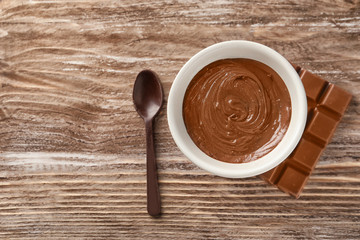 Bowl with molten chocolate on wooden background