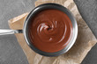 © Pixel-Shot - Bowl with tasty melted chocolate on grey table, top view