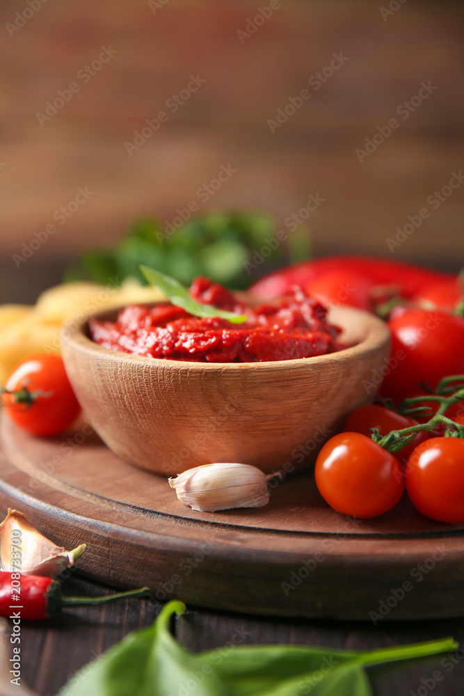 Bowl with red sauce and vegetables on table