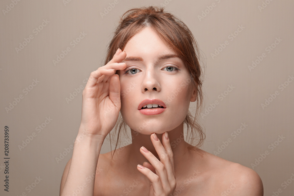 Beautiful young woman with silky skin on grey background