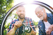 © Halfpoint - An adult hipster son and senior father repairing bicycle outside on a sunny day.