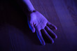 Open hand lying on the floor in dark blue light