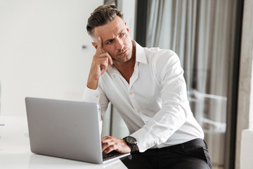 Canvas Print - Serious man dressed in formal clothes using laptop