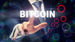 © Duncan Andison - A businessman pressing a Bitcoin business concept on a graphical display of cogs
