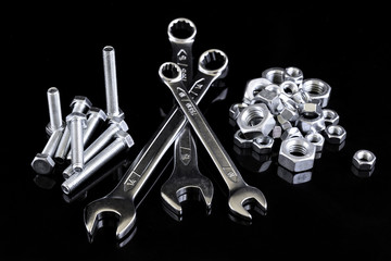 Wrenches, metal nuts and bolts isolated on black background.