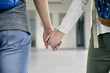 © PhotoAlto - Couple holding hands in corridor, cropped