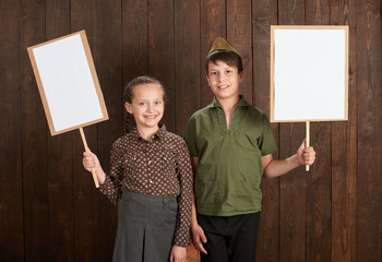 Children are dressed in retro military uniforms. They're holding blank posters for veterans portraits.