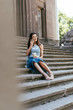 selective focus of young woman holding paper cup and talking by smartphone while sitting on stairs