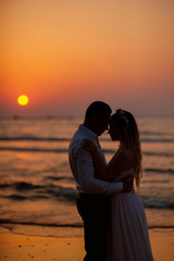 Wall Mural - Bride and groom, newlyweds, honeymoon on the beach sunset sun