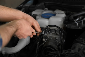 Auto mechanic repairing car in service center, closeup