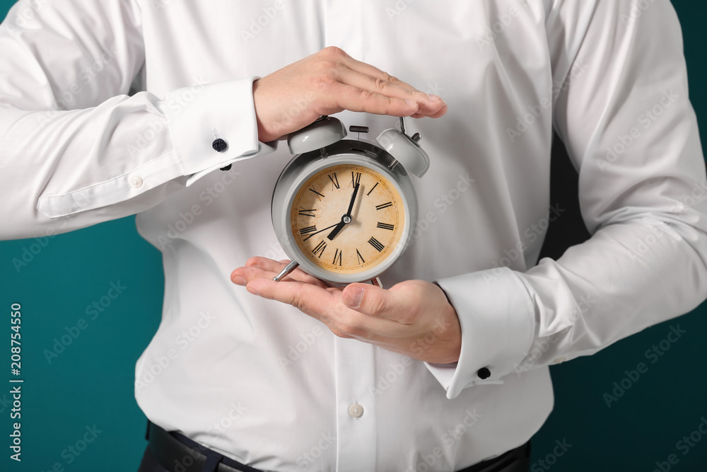 Man holding alarm clock on color background, closeup. Time management concept