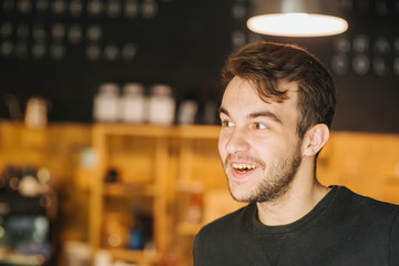 Poster - Portrait of handsome man. Always in good mood. Handsome young caucasian boy smiling and looking away while standing in front of the cafe outdoors