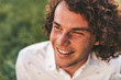 © Z A C - Close up shot of handsome happy young freckled male smiling with white toothy smile and curly hair posing in the city park looking a side. Copy space for your advertising.People, lifestyle and emotion