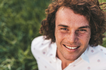 Close up outdoor portrait of happy handsome young male smiling with white toothy smile posing in the city park looking at the camera with copy space for your advertising. People, lifestyle and emotion