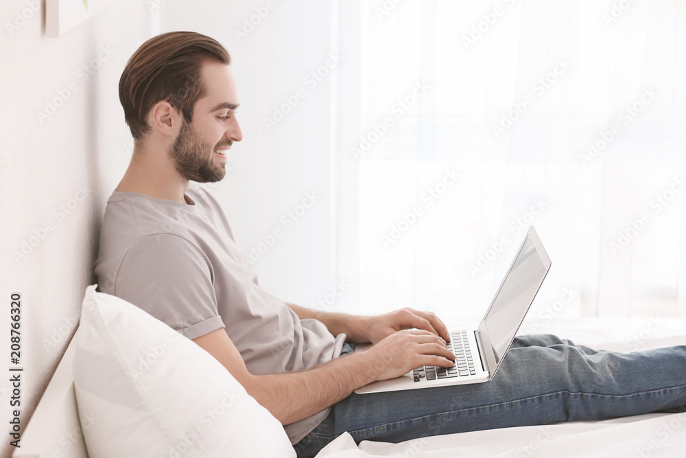 Male freelancer working with laptop in bed