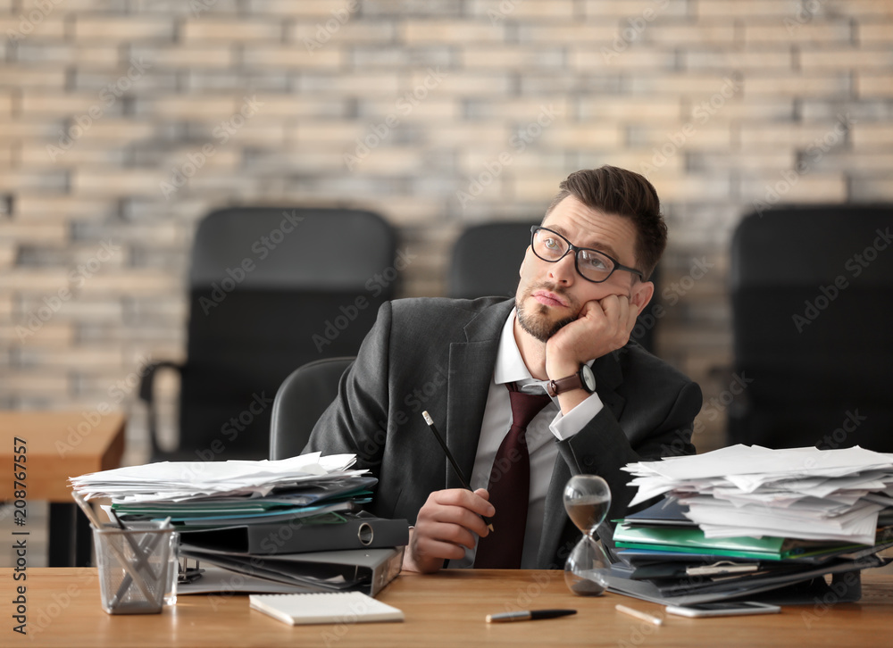 Tired mature businessman at table in office. Time management concept