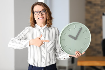 Mature woman with clock in office. Time management concept
