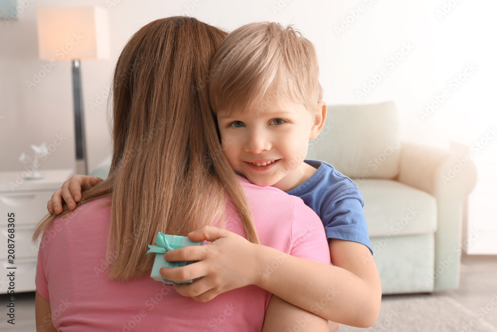 Mother receiving gift from her cute little son at home