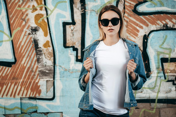 Girl wearing t-shirt and cotton jacket posing against street , urban clothing style. Street photography