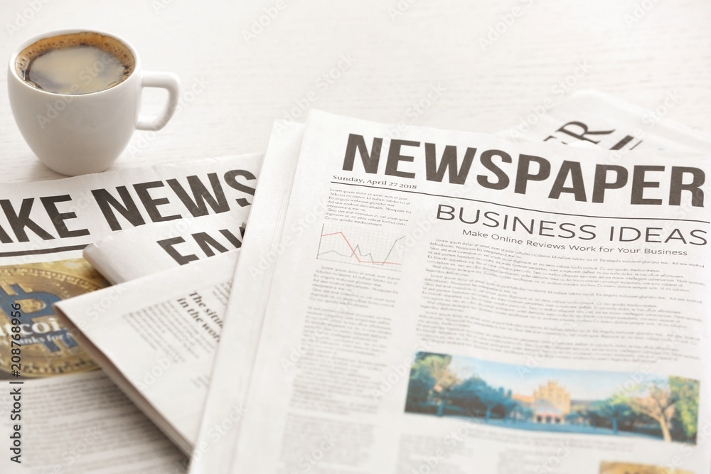 Morning newspapers and cup of hot coffee on white table