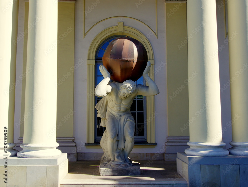 Atlas trzymający kulę - artystyczna rzeźba pomiędzy kolumnami przy wejściu do budynku - obrazy, fototapety, plakaty 