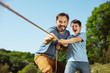 © zinkevych - Best team. Inspired loving father helping his son while he pulling a rope with his sister