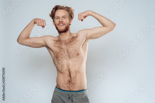 Photographie Bare redhead man shows muscles.