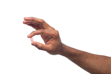 Wall Mural - Black hand holding a pill isolated on white background