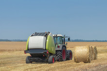 Tractor And Round Baler Discharges. Straw Bales.