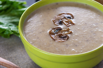 Cream of mushroom soup in a green bowl on the table. Autumn vegetarian traditional dish