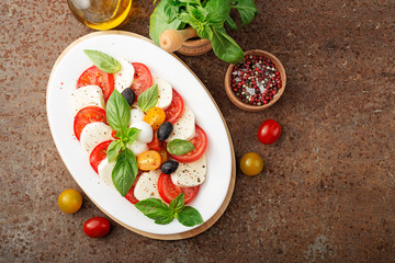 Wall Mural - Delicious caprese salad with  tomatoes,mozzarella cheese and fresh basil leaves. Italian food. top view