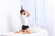 © be free - Good morning concept. Man in shirt sits on bed, white curtains on background, rear view. Macho with beard stretching, relaxing after nap. Picture showing young man stretching in bed.