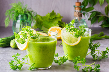 Refreshing smoothies from cucumber, green apple, fresh herbs and lemon juice in transparent glasses on the table. The concept of a healthy diet. Vegetarian menu