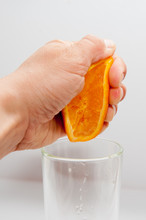 Hand Squeezes An Orange, Orange Juice In A Glass
