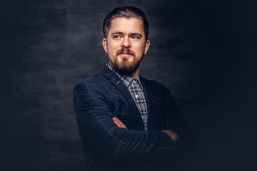 Close-up portrait of a middle-aged man with beard and hairstyle dressed in an elegant blue suit. Isolated on a textured dark background in studio.