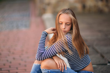 Wall Mural - young teenage poses to photographer. blonde girl in jeans and blouse