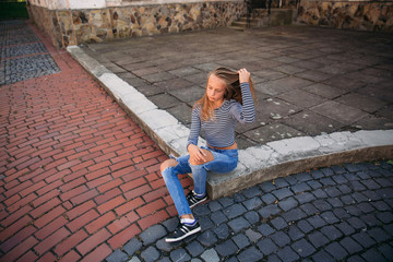 Wall Mural - young teenage poses to photographer. blonde girl in jeans and blouse