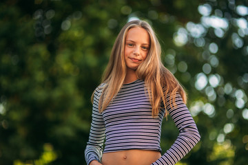 Wall Mural - blonde teenage girl in striped blouse on the backgrountd of green tree