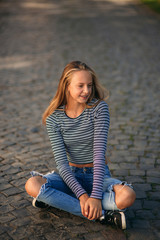 Wall Mural - a teenage girl in jeans and a blouse and sits in the middle of the street