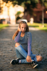 Wall Mural - a teenage girl in jeans and a blouse and sits in the middle of the street