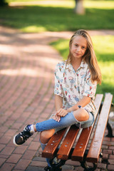 Wall Mural - young teenage girl sits on the bench