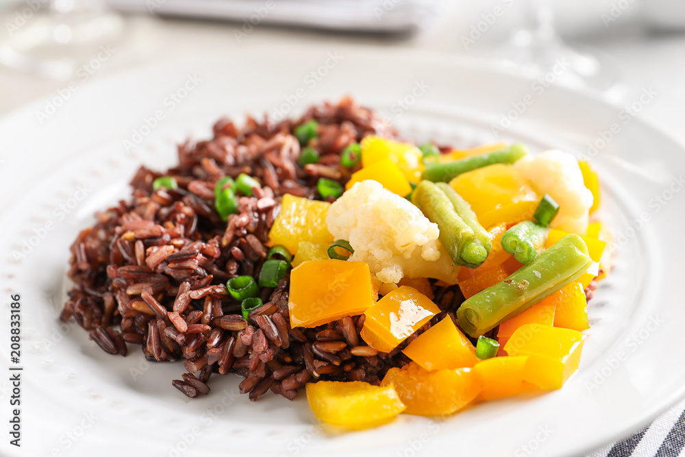Plate with delicious brown rice and vegetables, closeup