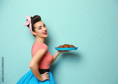 Funny young housewife with homemade pastry on color background Wallpaper Mural