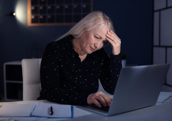 Wall Mural - Overworked mature woman with headache in office