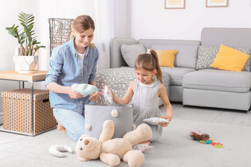 Wall Mural - Housewife and daughter picking up toys after playing at home