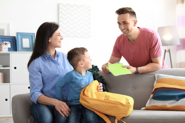 Wall Mural - Young parents helping their little child get ready for school at home