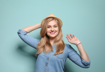 Attractive young woman in stylish outfit on color background