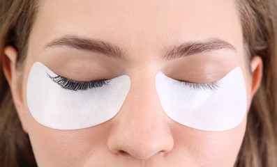 Poster - Young woman undergoing eyelash extensions procedure, closeup