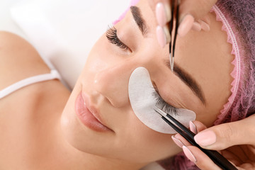 Young woman undergoing eyelash extensions procedure, closeup