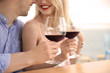 Young romantic couple with glasses of red wine at table
